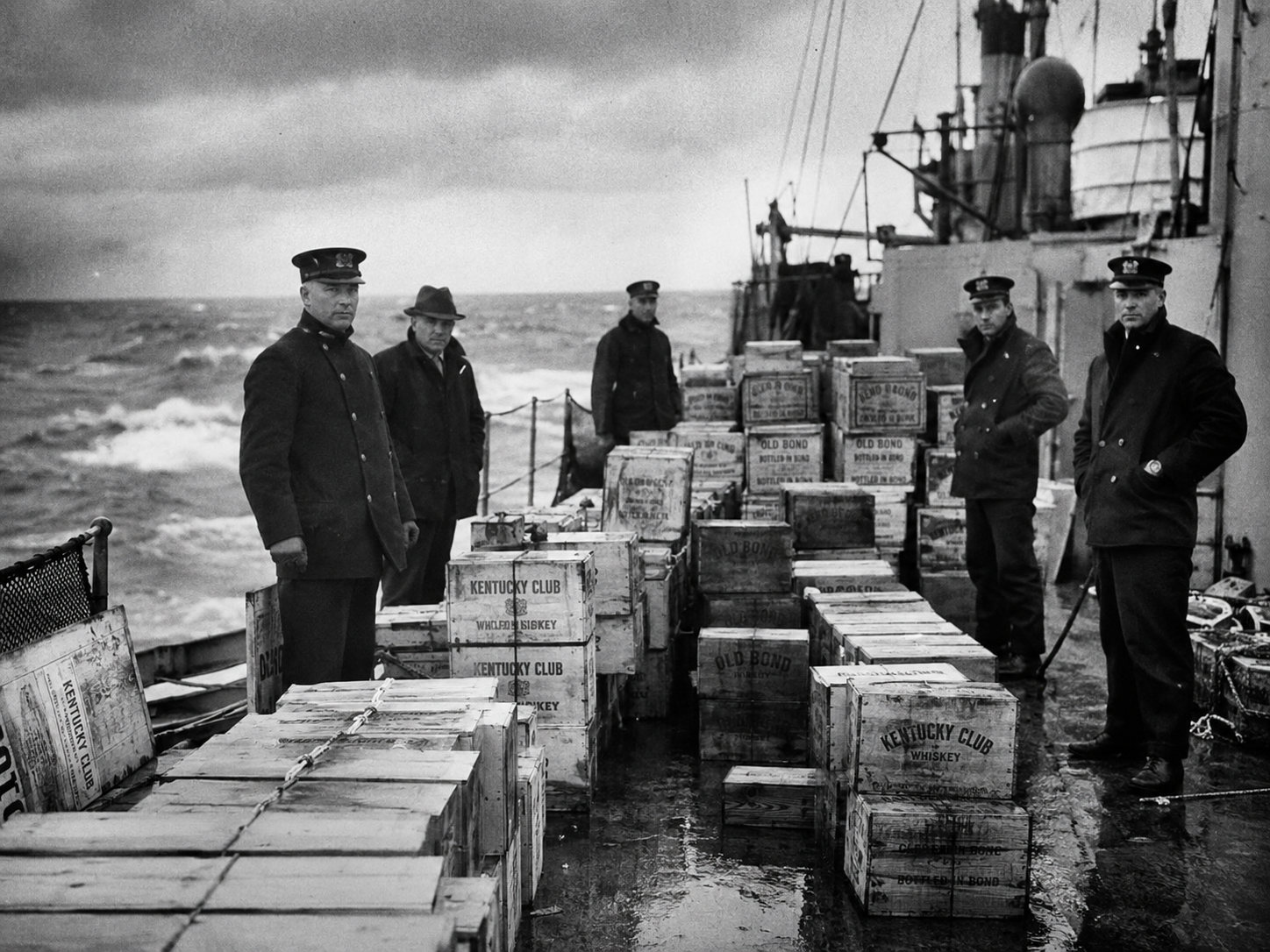 Offiziere der U.S. Coast Guard auf einem Schiff neben beschlagnahmten Whiskykisten
